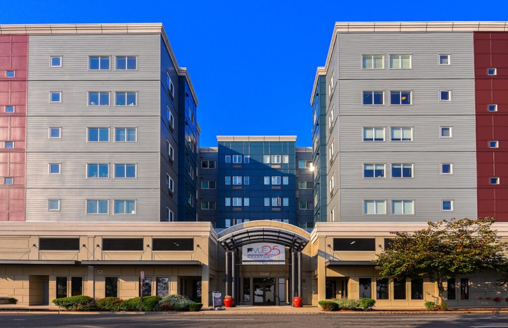 Vue 25 apartment building exterior, large multi story building with a landscaped sidewalk out front